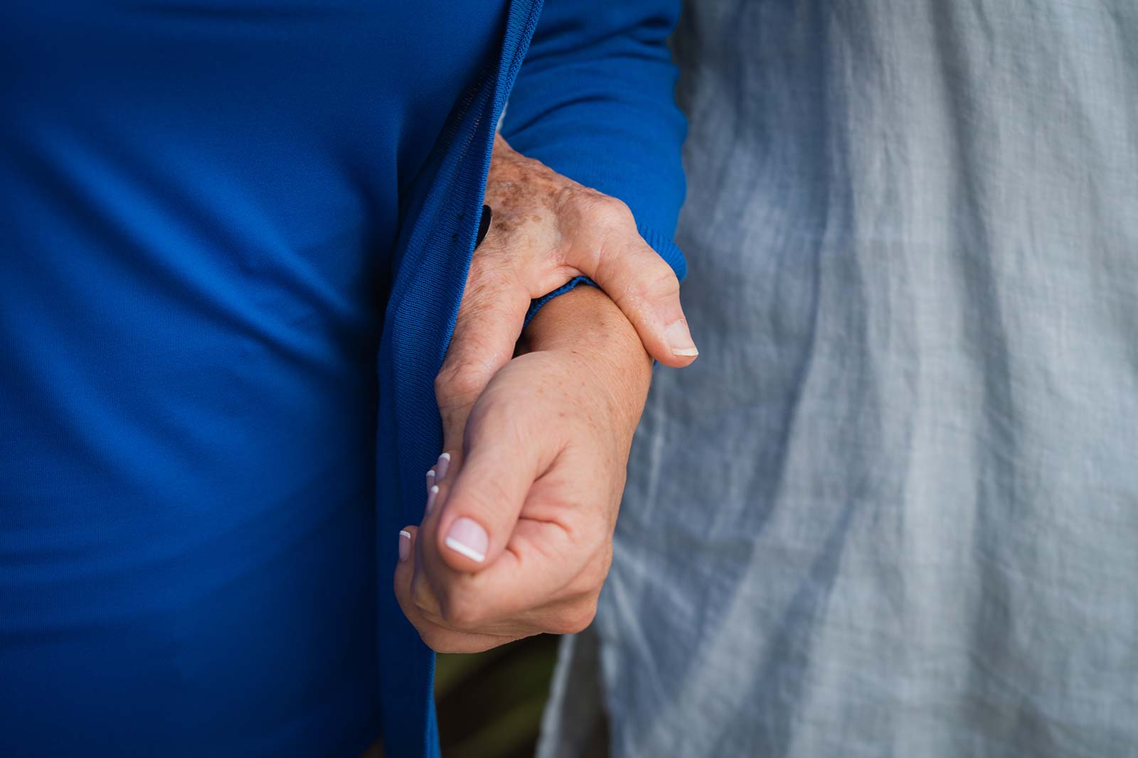 Close up of senior woman and staff member holding hands